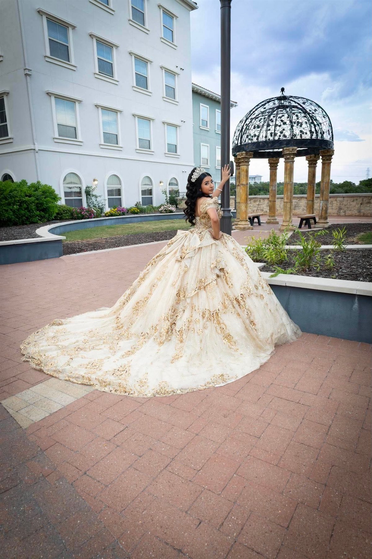 Quinceañera in a gold gown at a formal venue