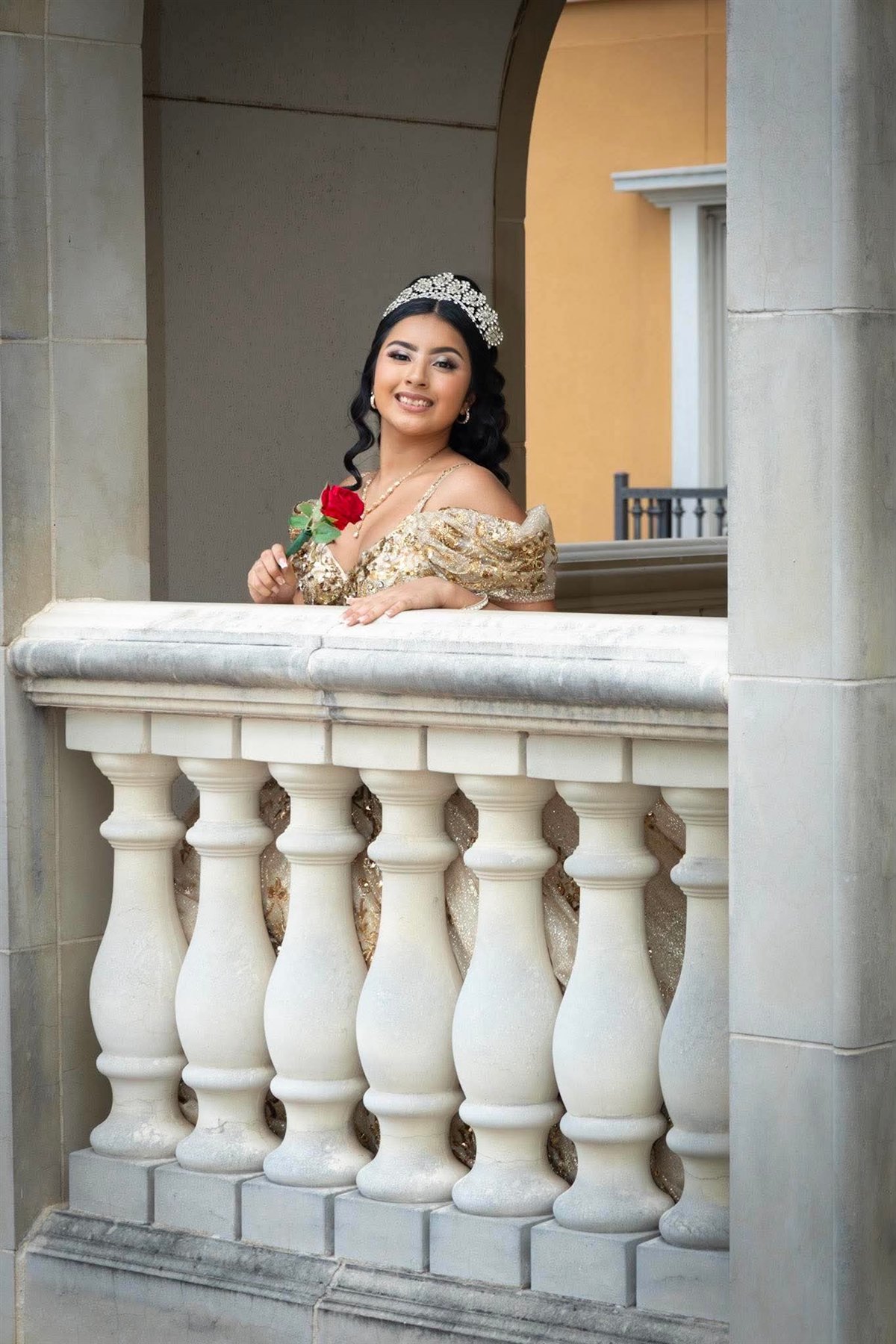 Quinceañera in a gold gown seated outside
