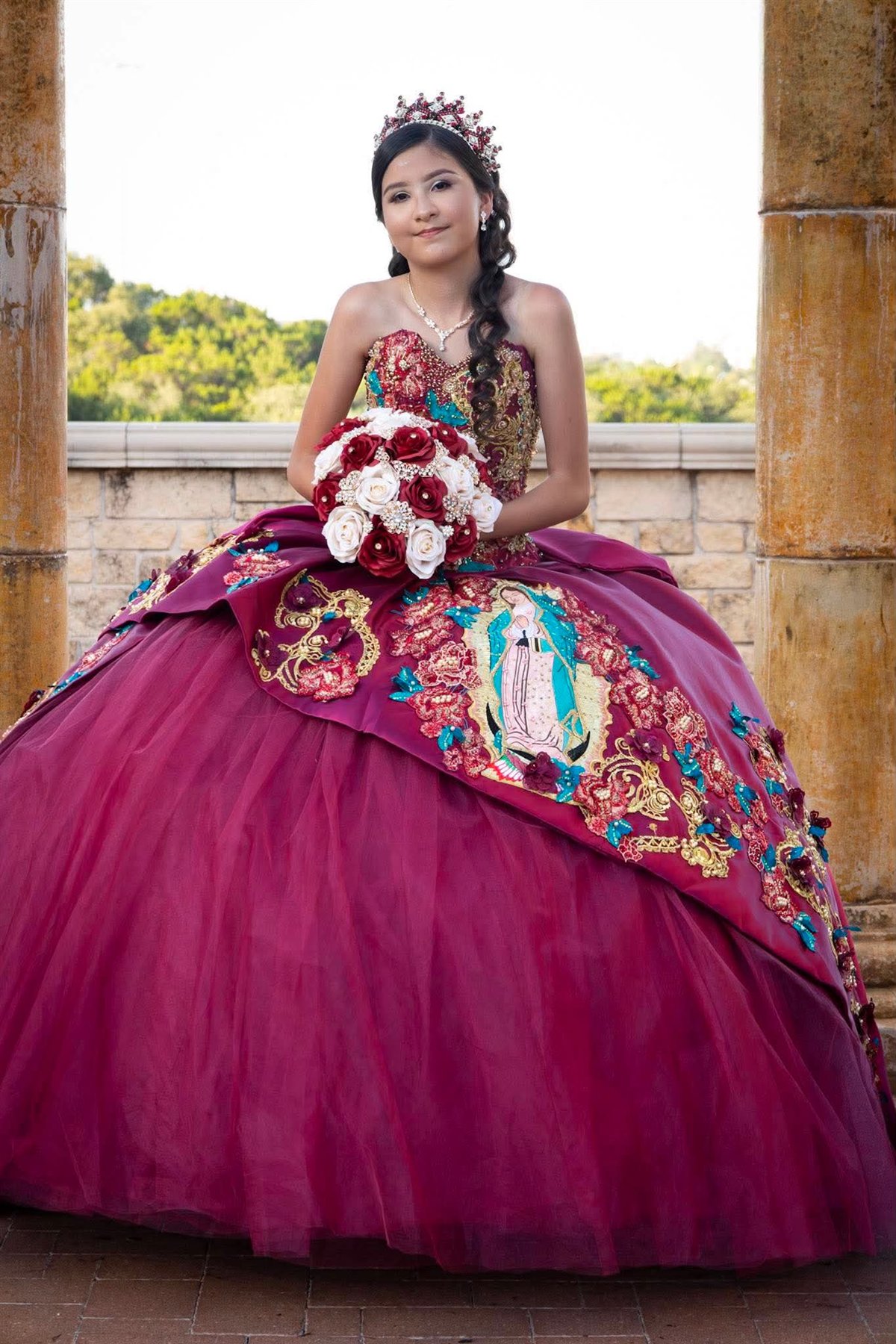 Quinceañera in a burgundy embroidered gown