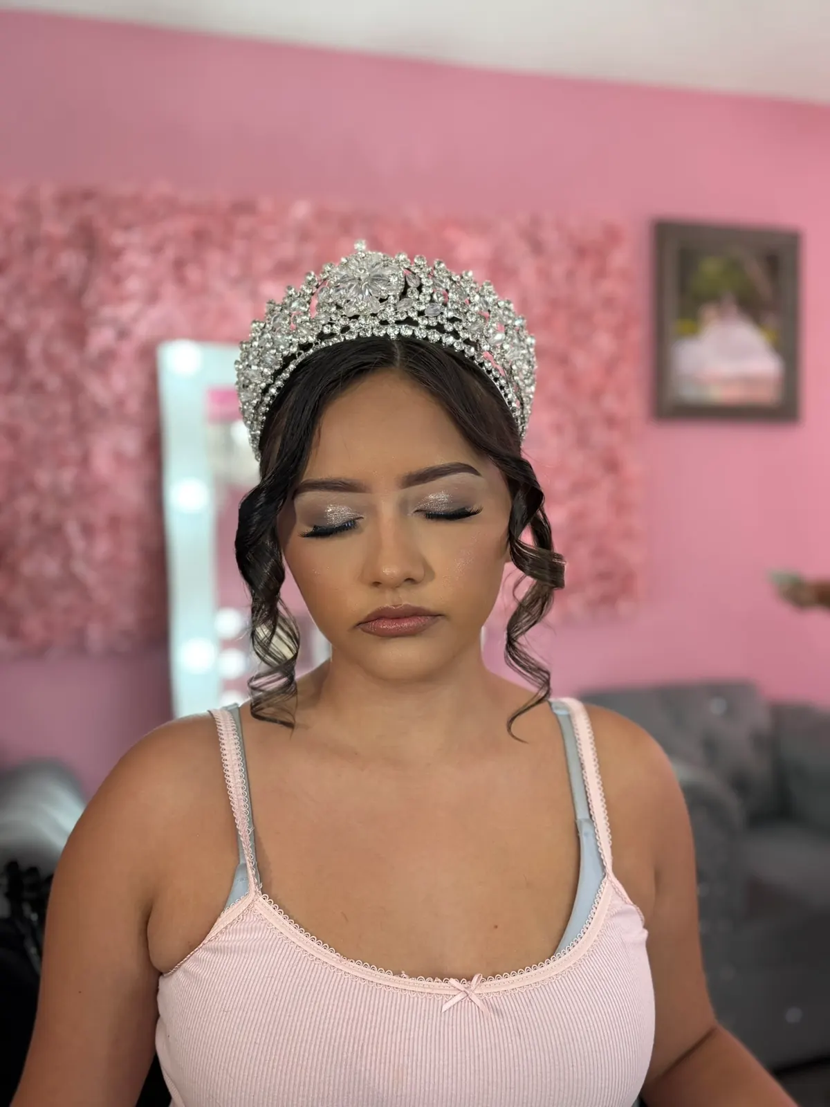 Quinceañera makeup look with tiara and curled hair