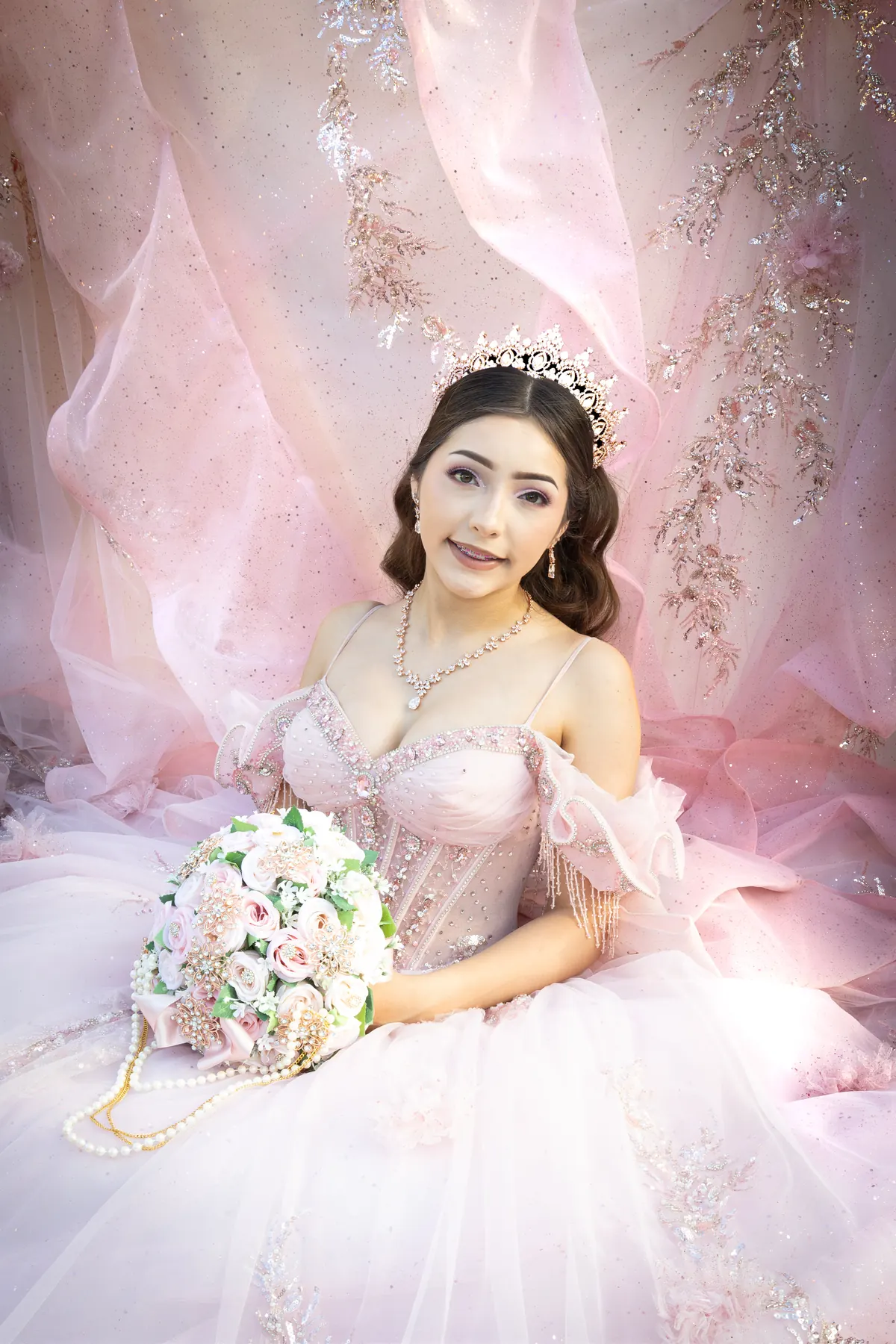 Quinceañera portrait in a blush gown with bouquet